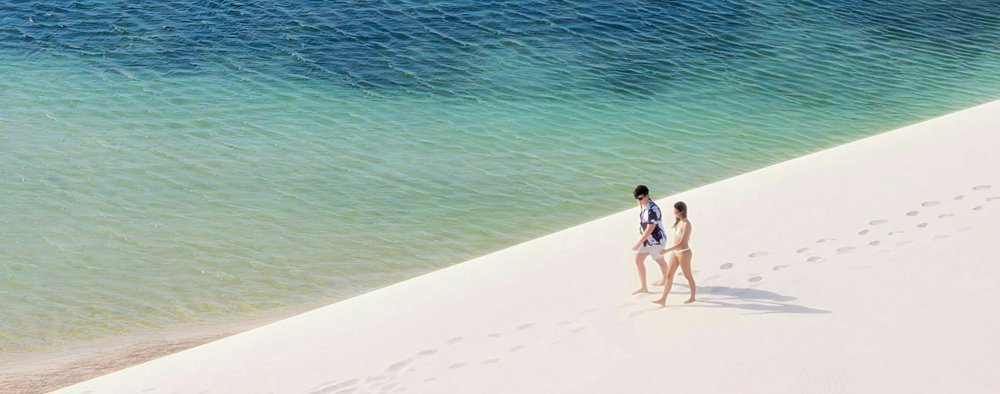 Beach shoreline with two people walking